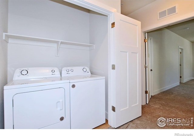 washroom featuring washing machine and dryer, light carpet, and baseboards