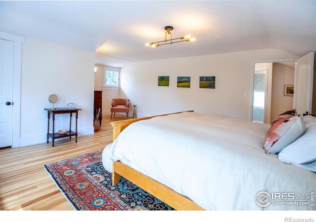 1114 5th Ave, Longmont, CO 80501 - bedroom featuring baseboards, a notable chandelier, wood finished floors, and lofted ceiling
