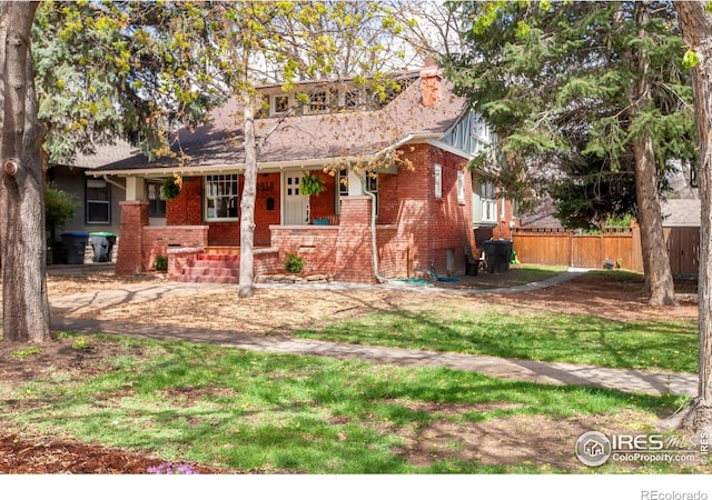 1114 5th Ave, Longmont, CO 80501 - view of front facade with brick siding, a front lawn, fence, and covered porch