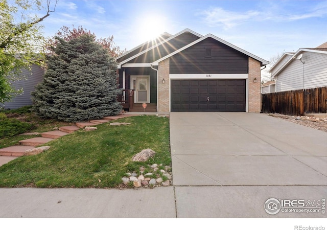 view of front facade featuring a garage, fence, a front yard, brick siding, and driveway