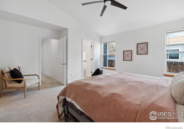 bedroom with carpet, multiple windows, ensuite bathroom, and lofted ceiling