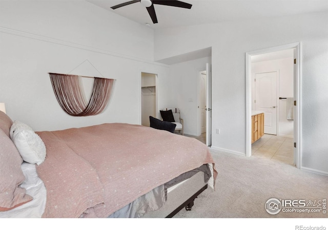 bedroom with a walk in closet, vaulted ceiling, baseboards, connected bathroom, and light carpet