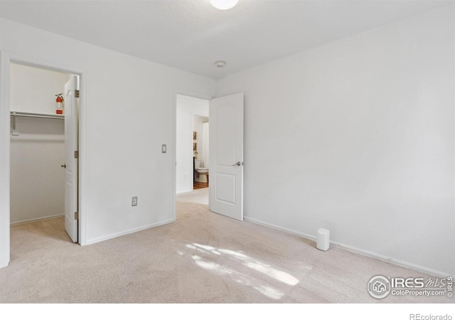 unfurnished bedroom with carpet floors, baseboards, a closet, and a walk in closet