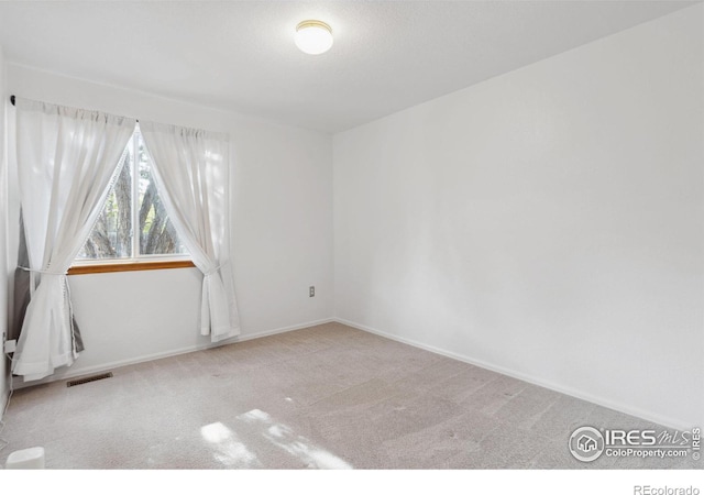 carpeted spare room featuring baseboards and visible vents