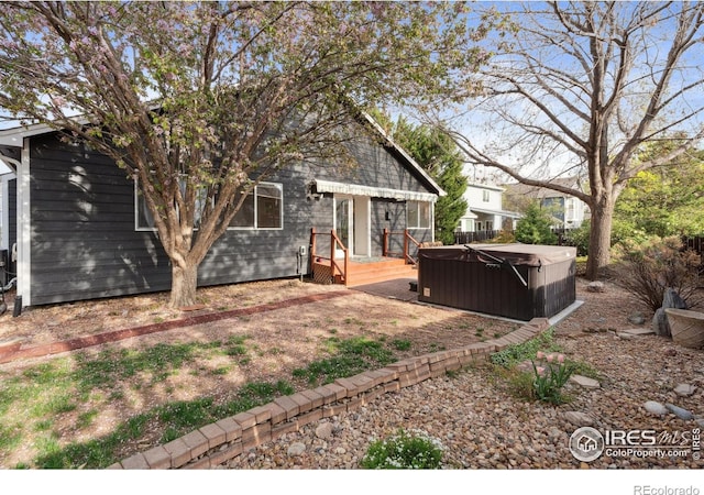 rear view of property featuring a hot tub