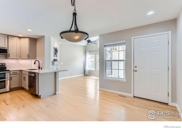 kitchen featuring gray cabinets, visible vents, appliances with stainless steel finishes, a sink, and a peninsula