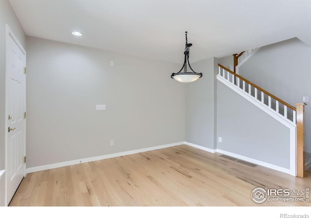 unfurnished dining area featuring baseboards, recessed lighting, wood finished floors, and stairs