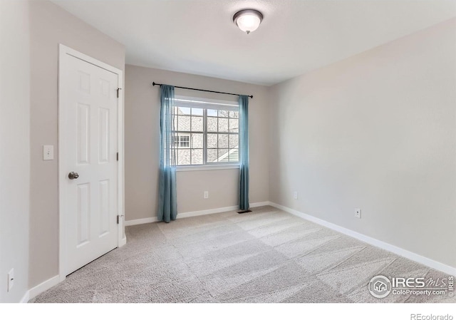 carpeted spare room featuring baseboards