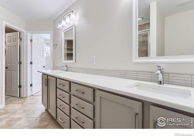full bath with a sink, tile patterned floors, a shower stall, and double vanity
