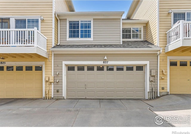 exterior space featuring an attached garage, a balcony, and driveway