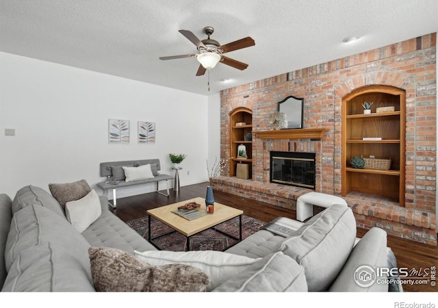 living room featuring a ceiling fan, a textured ceiling, built in features, and wood finished floors
