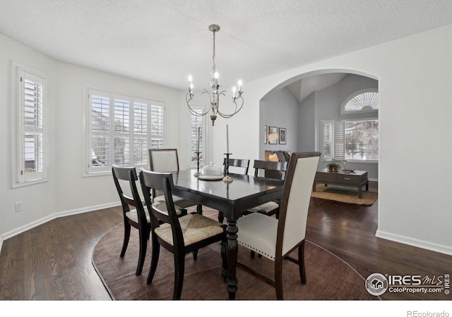 dining area featuring a notable chandelier, arched walkways, a textured ceiling, baseboards, and dark wood-style floors