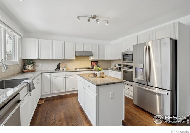 kitchen featuring appliances with stainless steel finishes, a center island, a sink, under cabinet range hood, and white cabinetry