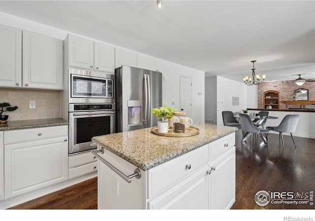kitchen featuring dark wood-style floors, white cabinets, light stone counters, a notable chandelier, and stainless steel appliances