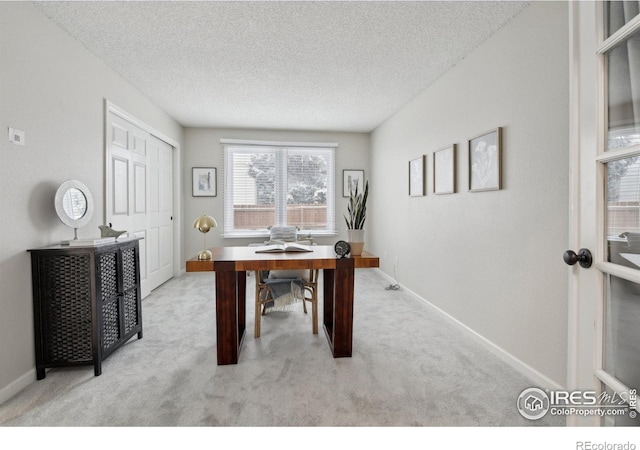 carpeted home office featuring baseboards and a textured ceiling