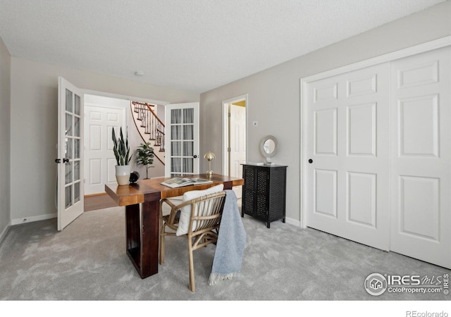 carpeted dining space featuring french doors, a textured ceiling, baseboards, and stairway