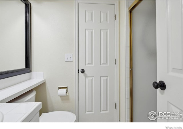 full bath with vanity, a shower with door, and toilet
