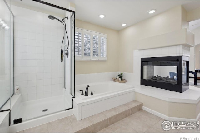 bathroom featuring a garden tub, a fireplace, a stall shower, tile patterned floors, and recessed lighting