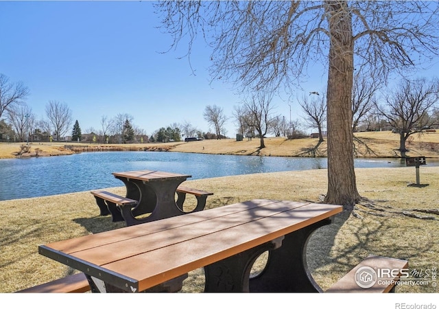 view of dock with a lawn and a water view
