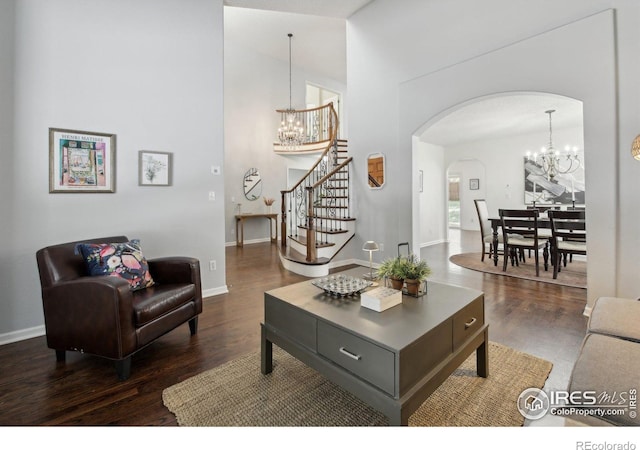 living room featuring arched walkways, dark wood-style flooring, stairs, and a chandelier