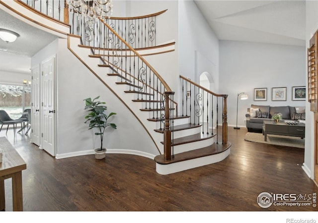 stairs featuring a high ceiling, wood finished floors, and a chandelier