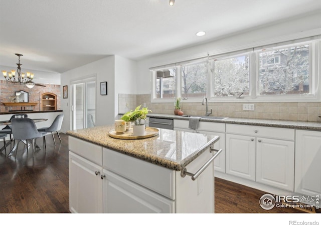 kitchen featuring backsplash, an inviting chandelier, a sink, and dark wood finished floors
