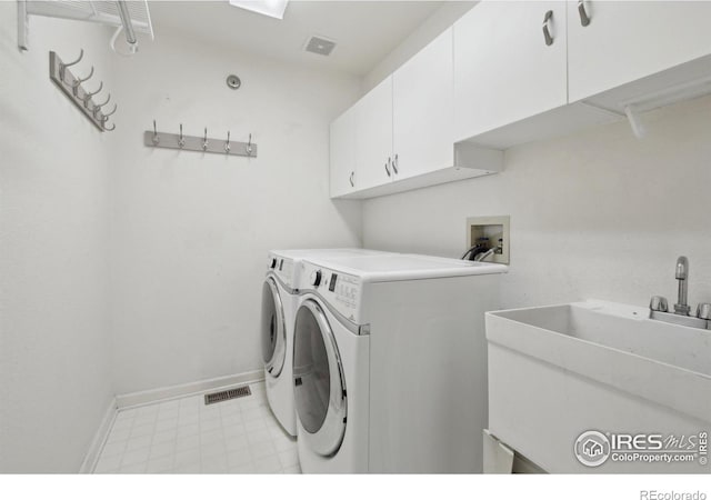 clothes washing area with visible vents, baseboards, washer and clothes dryer, a sink, and cabinet space