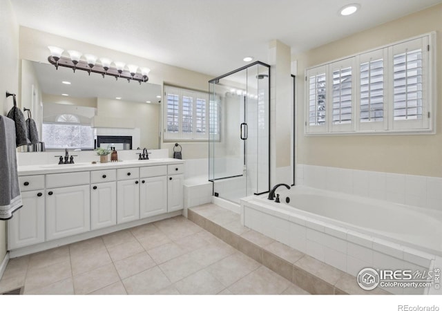 bathroom featuring double vanity, a garden tub, tile patterned flooring, a stall shower, and a sink