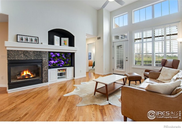 living room featuring plenty of natural light, a towering ceiling, wood finished floors, and visible vents