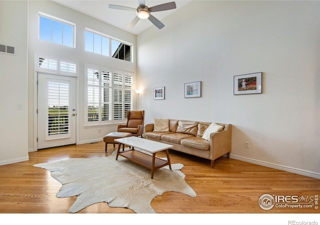 living room featuring a ceiling fan, visible vents, a wealth of natural light, and light wood-style flooring