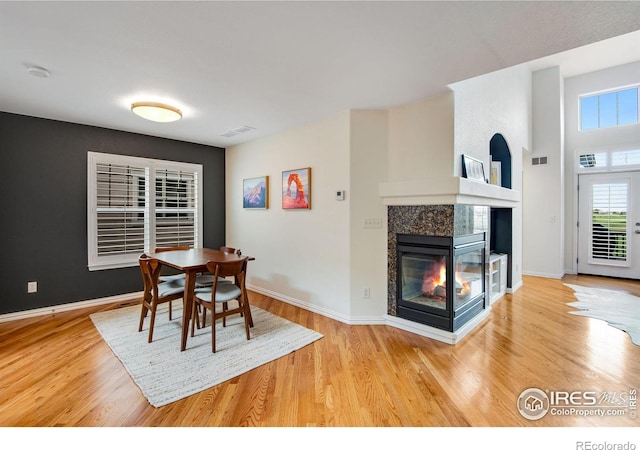 dining area featuring baseboards, a fireplace, wood finished floors, and visible vents