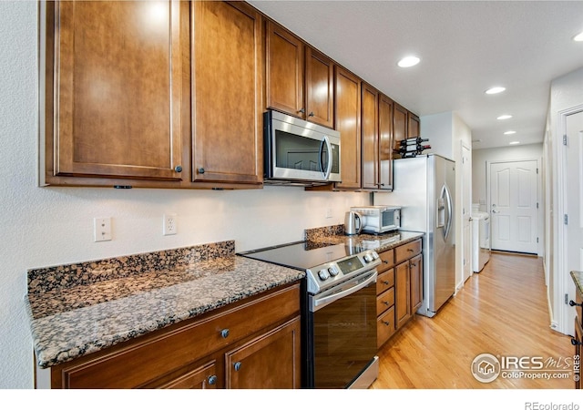 kitchen with dark stone counters, stainless steel appliances, recessed lighting, and light wood-style flooring