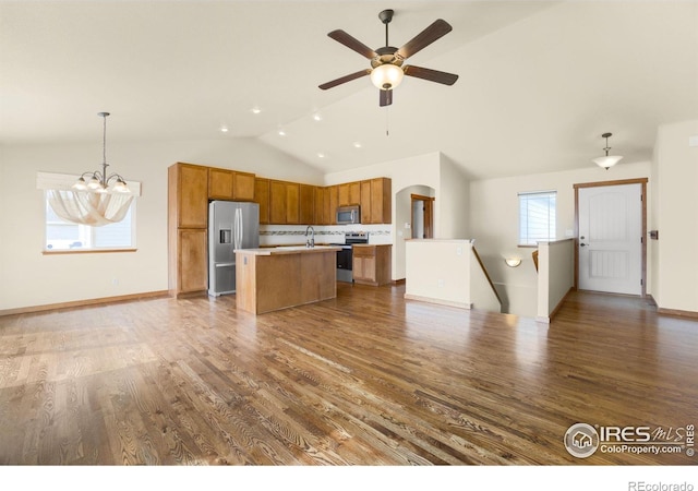 7056 Langland St, Wellington, CO 80549 - kitchen with stainless steel appliances, lofted ceiling, brown cabinets, open floor plan, and wood finished floors