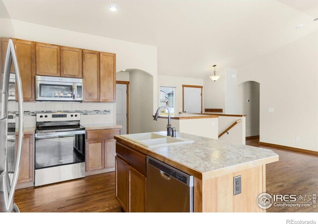 7056 Langland St, Wellington, CO 80549 - kitchen featuring stainless steel appliances, arched walkways, a sink, dark wood-style floors, and recessed lighting