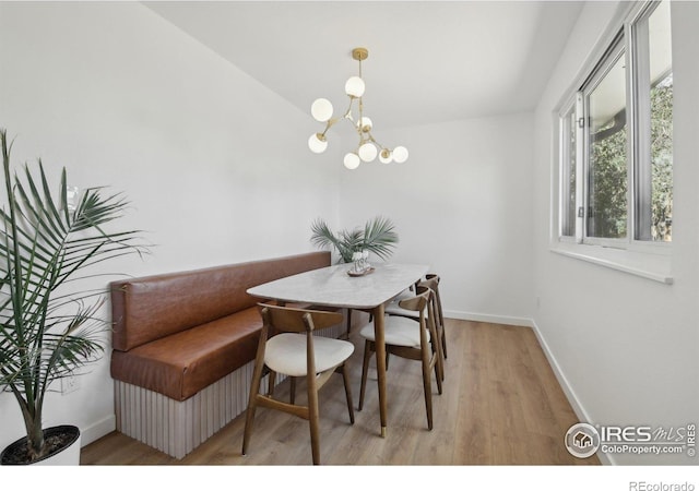 dining space featuring baseboards, an inviting chandelier, and light wood-style floors