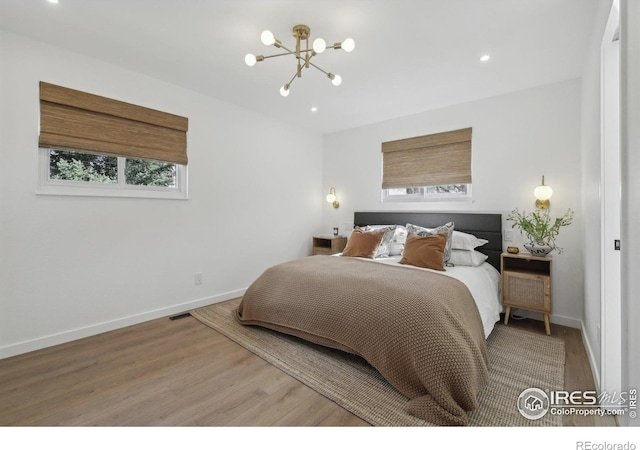 bedroom featuring baseboards, recessed lighting, wood finished floors, and a notable chandelier