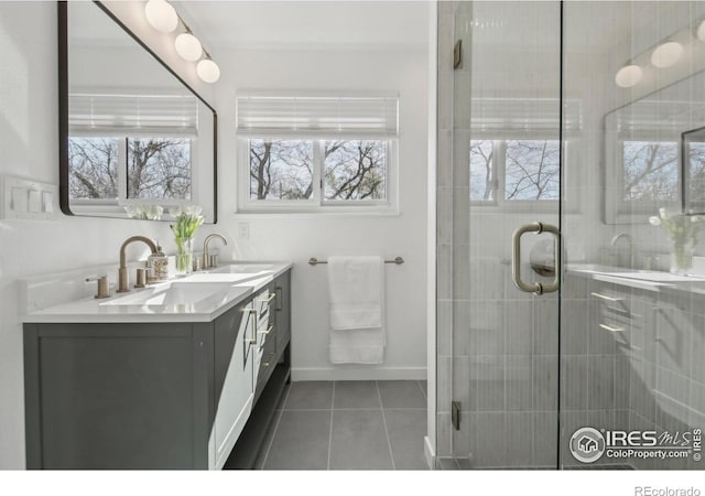 bathroom featuring double vanity, tile patterned floors, a shower stall, and a sink
