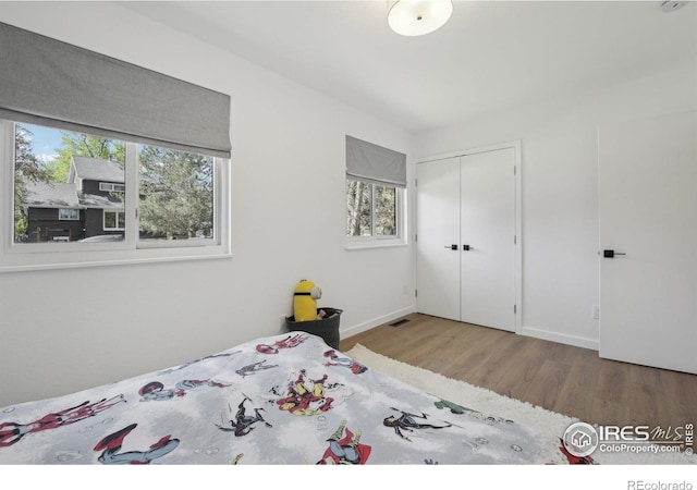 bedroom featuring visible vents, multiple windows, wood finished floors, and a closet
