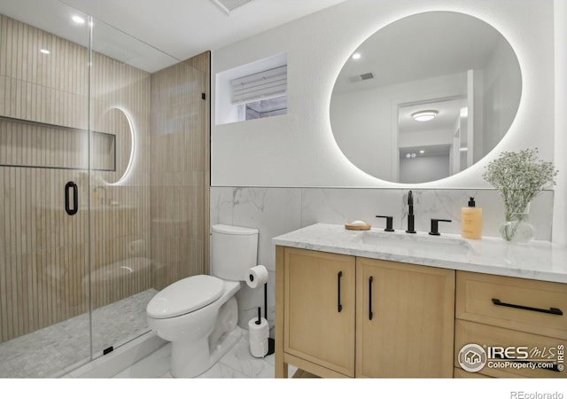 bathroom with tile walls, a stall shower, vanity, toilet, and marble finish floor