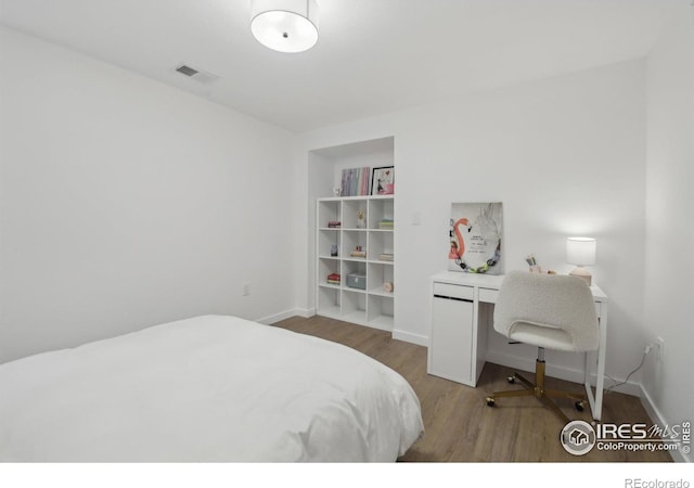 bedroom featuring baseboards, wood finished floors, and visible vents