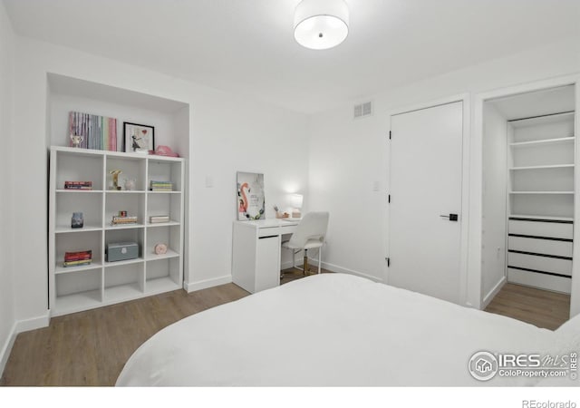 bedroom featuring baseboards, visible vents, and wood finished floors