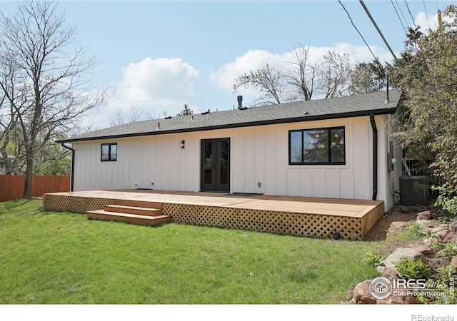 rear view of house with french doors, a wooden deck, central air condition unit, fence, and a yard