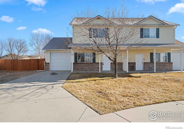 traditional-style house featuring fence, an attached garage, brick siding, concrete driveway, and covered porch