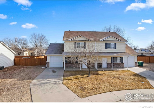 traditional home featuring concrete driveway, fence, a porch, and a garage