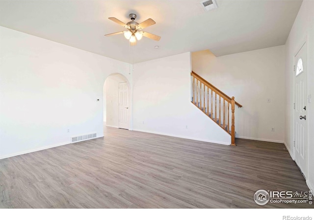 interior space featuring arched walkways, a ceiling fan, stairs, and visible vents