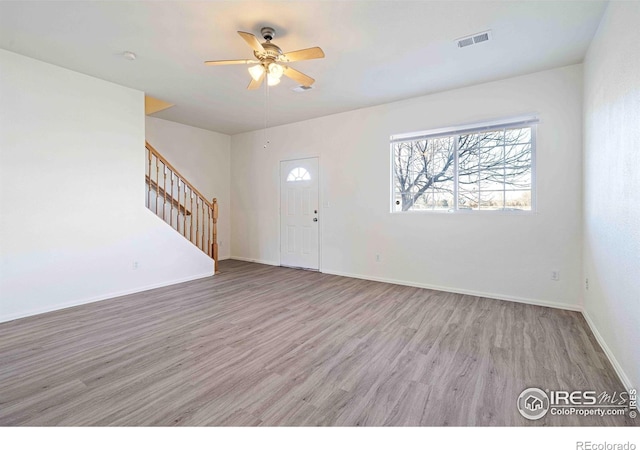 entryway featuring visible vents, stairs, wood finished floors, baseboards, and ceiling fan