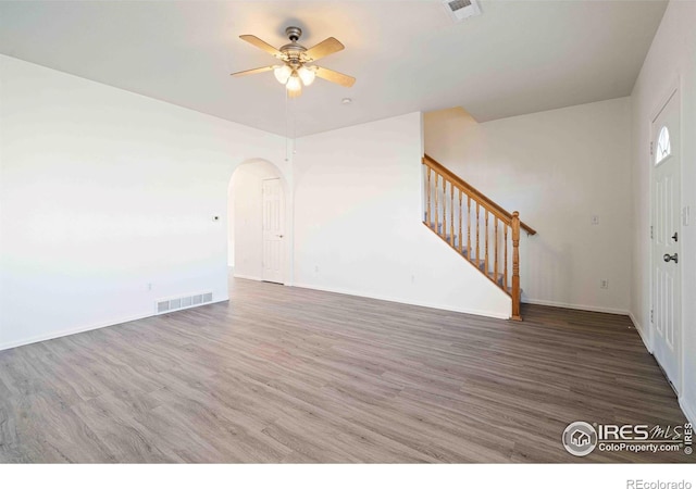 unfurnished living room with visible vents, a ceiling fan, arched walkways, and stairway