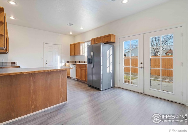 kitchen featuring french doors, stainless steel refrigerator with ice dispenser, light wood-type flooring, dishwasher, and recessed lighting