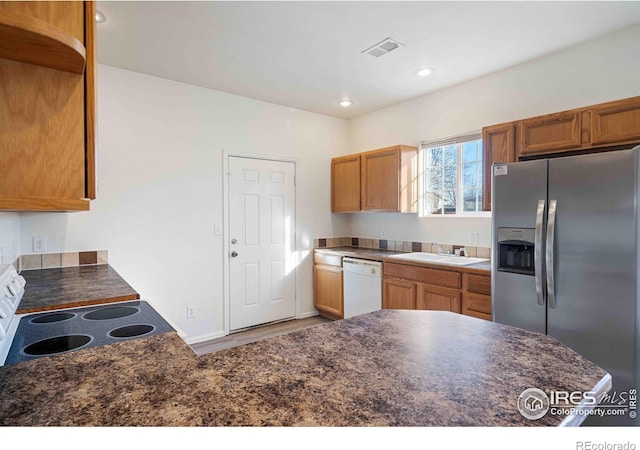 kitchen with stainless steel refrigerator with ice dispenser, white dishwasher, electric range oven, and dark countertops