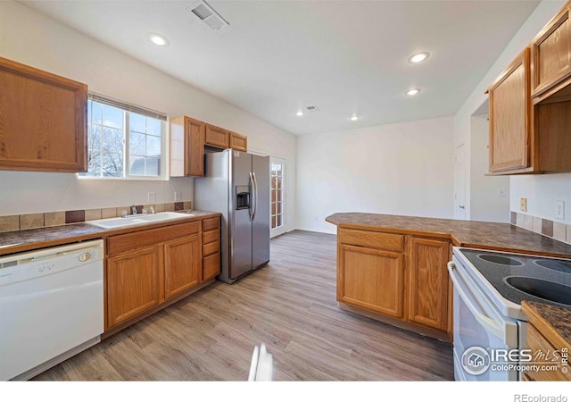 kitchen with a sink, white appliances, light wood-style flooring, recessed lighting, and visible vents